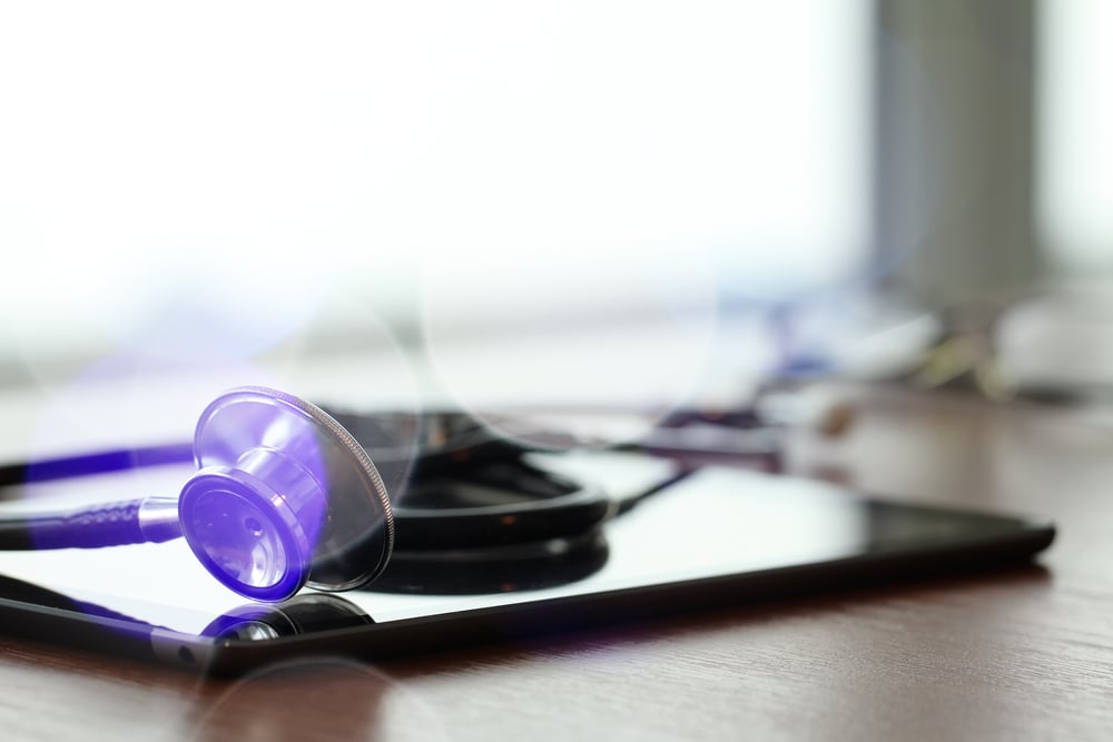 Studio macro of a stethoscope and digital tablet with shallow DOF evenly matched abstract on wood table background copy space