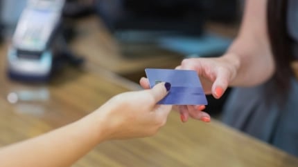 Woman handing over credit card at cash register