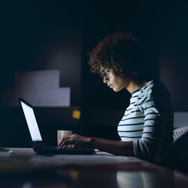 Woman in a dim lit room working on laptop